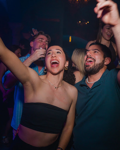 Ecstatic partygoers dancing under laser canopy